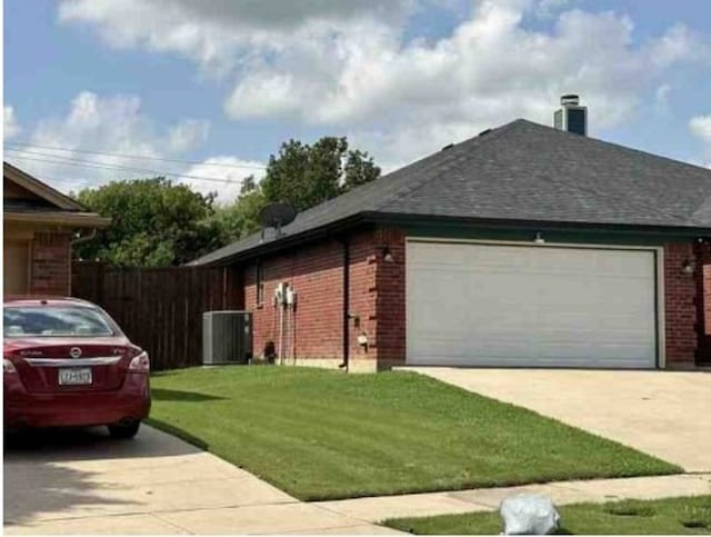 view of side of home with central AC, a yard, and a garage