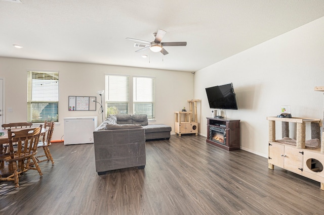 living room featuring dark wood-type flooring and ceiling fan