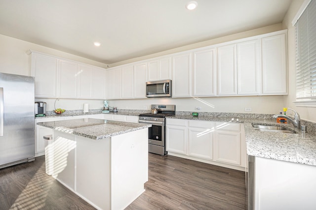 kitchen with appliances with stainless steel finishes, sink, a center island, white cabinetry, and dark hardwood / wood-style floors