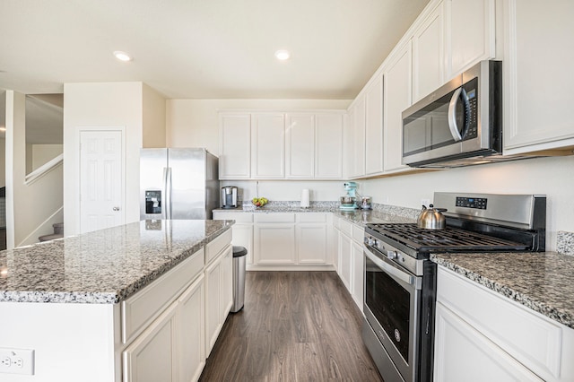 kitchen with light stone countertops, a kitchen island, white cabinetry, stainless steel appliances, and dark wood-type flooring