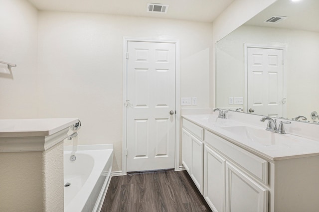 bathroom with vanity, hardwood / wood-style floors, and a tub to relax in