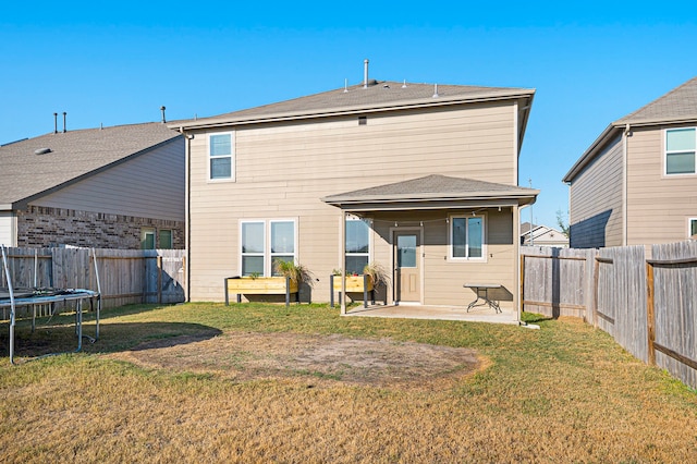 back of property with a patio, a trampoline, and a lawn