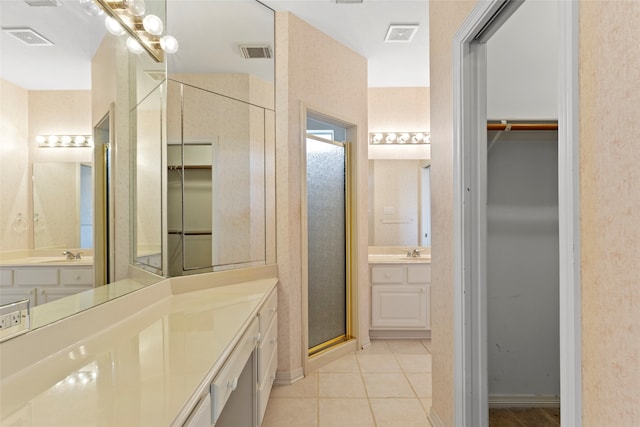 bathroom featuring two vanities, a spacious closet, tile patterned floors, a shower stall, and baseboards