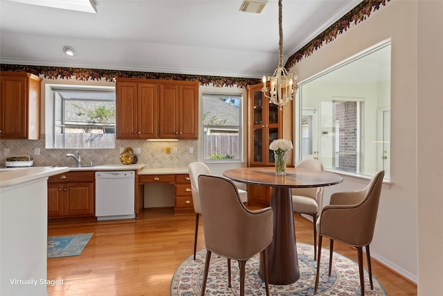 dining room with a chandelier, healthy amount of natural light, light wood-style floors, and ornamental molding