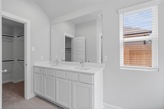 bathroom featuring plenty of natural light, vanity, and vaulted ceiling