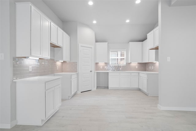 kitchen featuring white cabinets, light wood-type flooring, sink, and backsplash