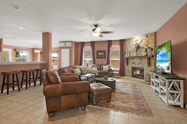 tiled living room featuring ceiling fan and a stone fireplace