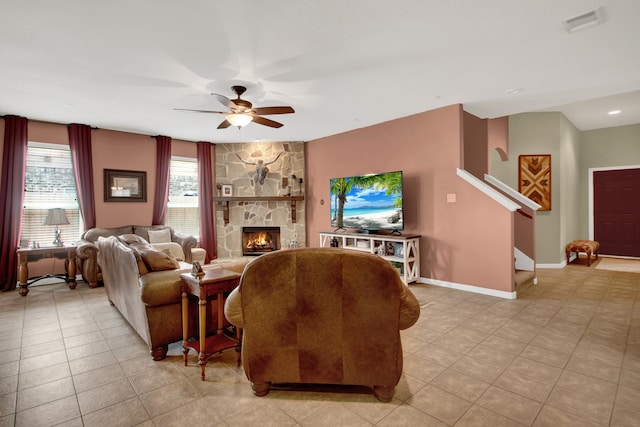 living room featuring light tile patterned floors, a fireplace, and ceiling fan