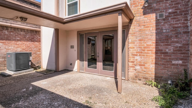 view of exterior entry with a patio, french doors, and central AC unit