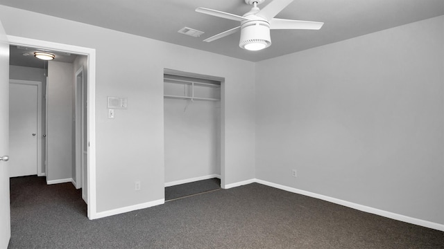 unfurnished bedroom with dark colored carpet, a closet, and ceiling fan