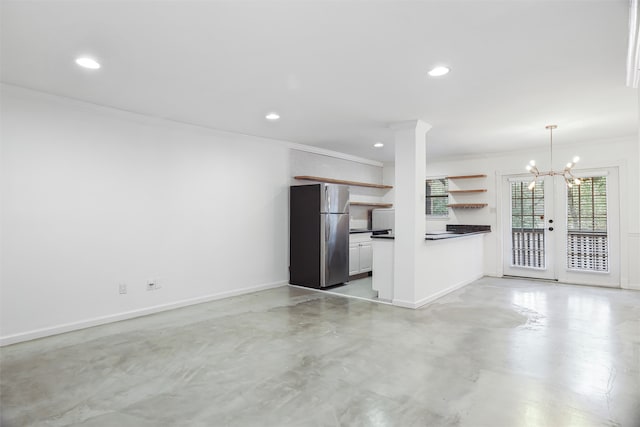 unfurnished living room with french doors, ornamental molding, and a notable chandelier