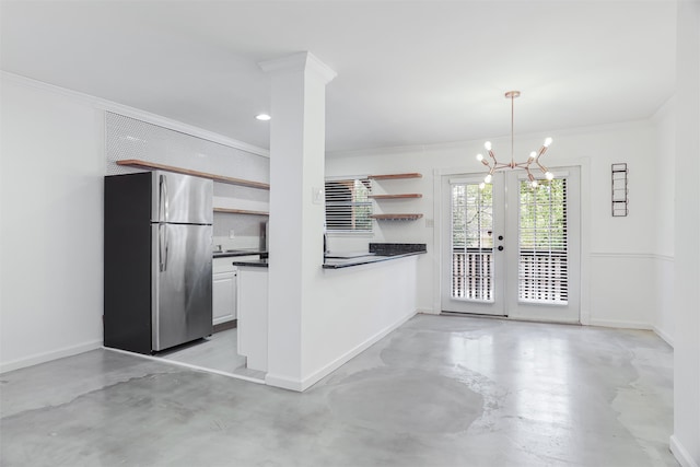 kitchen with stainless steel refrigerator, white cabinetry, ornate columns, a chandelier, and decorative light fixtures