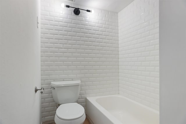 bathroom featuring toilet and tiled shower / bath