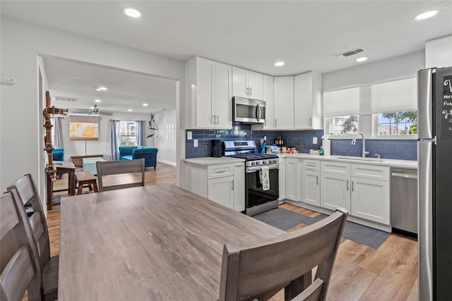 kitchen with light hardwood / wood-style flooring, appliances with stainless steel finishes, sink, and white cabinets