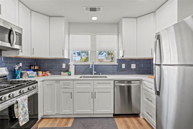 kitchen with white cabinetry, appliances with stainless steel finishes, sink, and light wood-type flooring