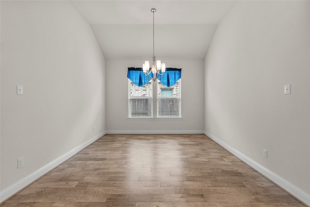 unfurnished dining area with an inviting chandelier, wood-type flooring, and vaulted ceiling