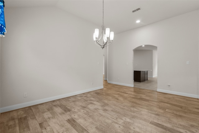 spare room with a notable chandelier, lofted ceiling, and light hardwood / wood-style flooring