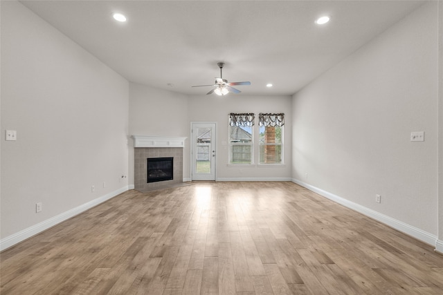 unfurnished living room featuring light hardwood / wood-style floors, a tile fireplace, and ceiling fan