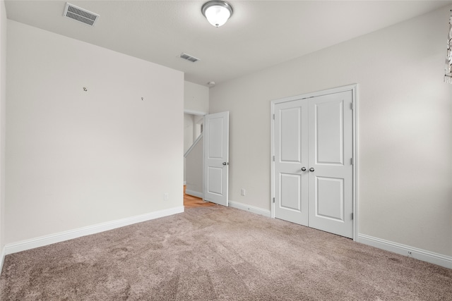 unfurnished bedroom featuring light colored carpet and a closet