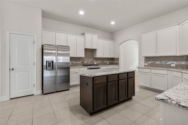 kitchen featuring stainless steel fridge, white cabinets, and backsplash