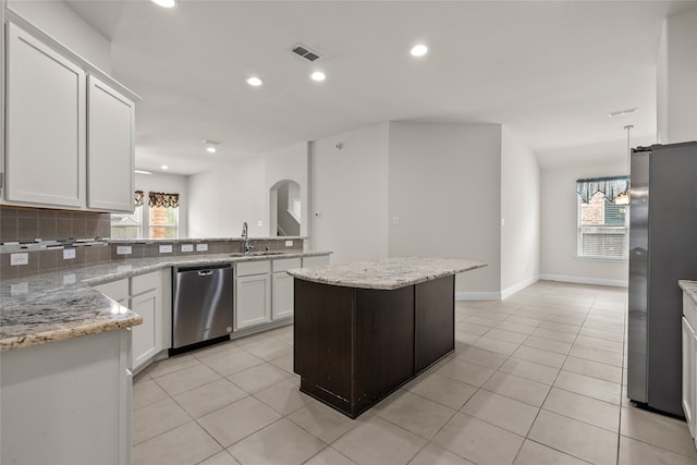 kitchen featuring a kitchen island, white cabinets, a chandelier, appliances with stainless steel finishes, and tasteful backsplash