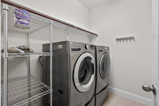 laundry area with washer and clothes dryer and light tile patterned floors