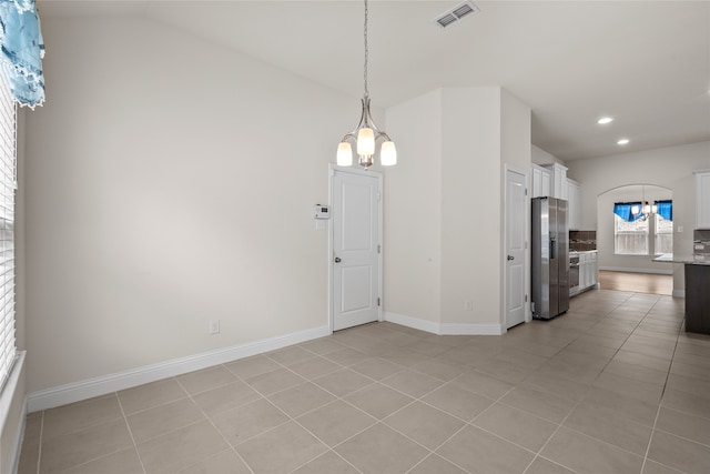 interior space with light tile patterned flooring, vaulted ceiling, white cabinets, stainless steel fridge with ice dispenser, and a chandelier