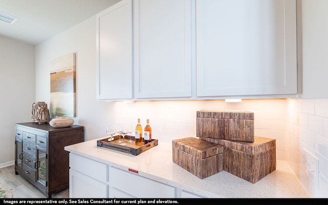 kitchen featuring light stone counters, decorative backsplash, light wood-type flooring, and white cabinets