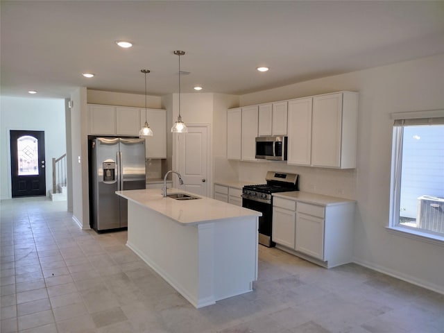 kitchen with pendant lighting, an island with sink, sink, white cabinets, and stainless steel appliances