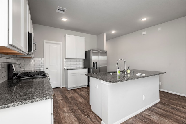 kitchen with dark wood-type flooring, stainless steel appliances, an island with sink, and white cabinets