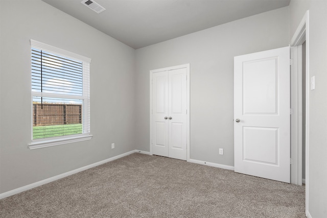 unfurnished bedroom with light colored carpet and a closet