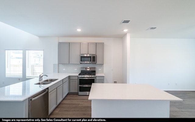 kitchen with appliances with stainless steel finishes, sink, kitchen peninsula, and hardwood / wood-style floors