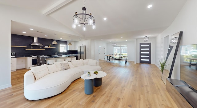 living room with light hardwood / wood-style flooring, lofted ceiling with beams, and a chandelier