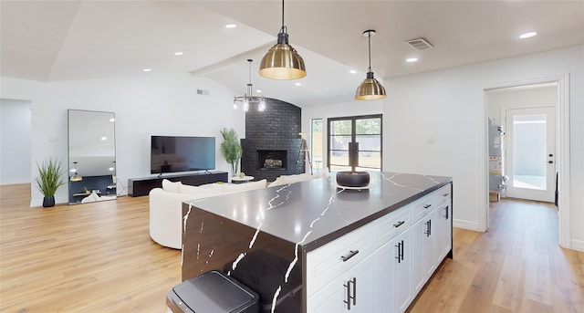 kitchen featuring white cabinets, a kitchen island, light wood-type flooring, pendant lighting, and lofted ceiling with beams