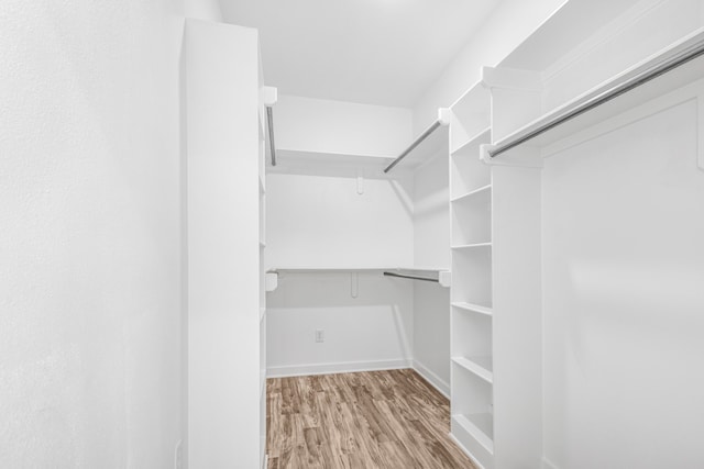 walk in closet with light hardwood / wood-style floors