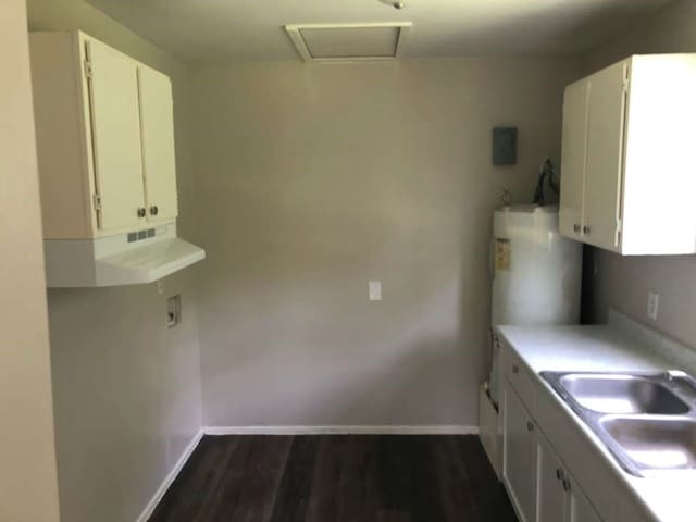 kitchen with sink, white cabinets, dark wood-type flooring, and water heater