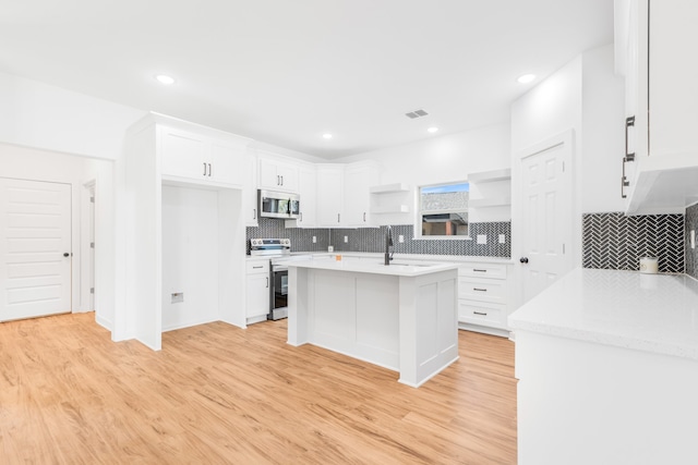 kitchen featuring white cabinets, a center island with sink, stainless steel appliances, and light hardwood / wood-style flooring