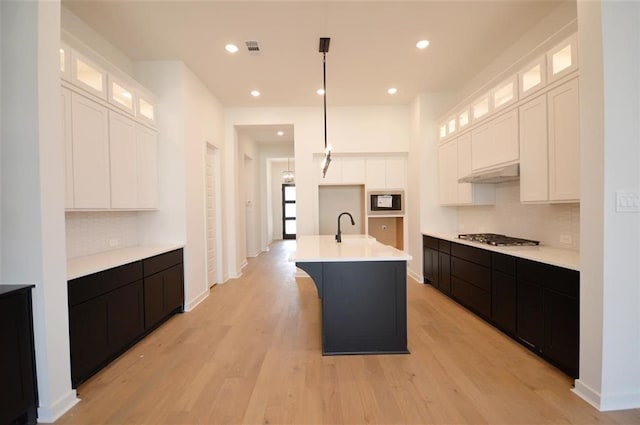 kitchen with a center island with sink, white cabinets, and backsplash