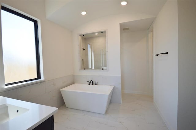 bathroom with vaulted ceiling, a tub, vanity, and plenty of natural light