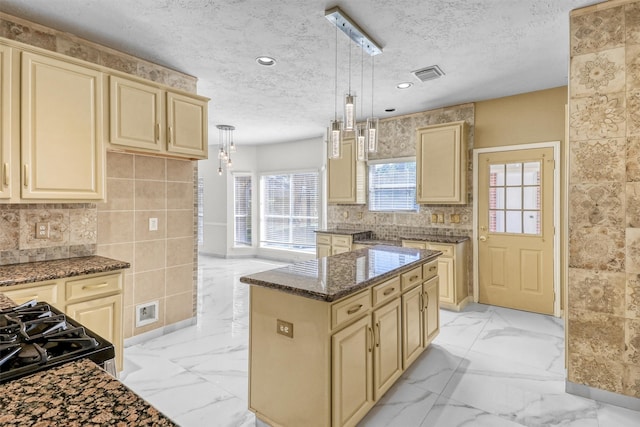 kitchen featuring pendant lighting, dark stone countertops, a center island, gas stove, and a textured ceiling