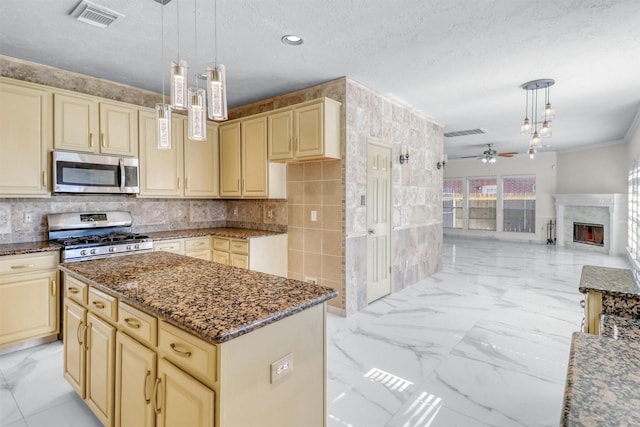 kitchen with decorative light fixtures, a center island, dark stone counters, and appliances with stainless steel finishes