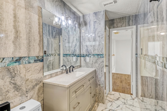 bathroom featuring vanity, tile walls, and a textured ceiling