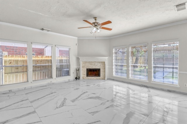 living room featuring ornamental molding, a stone fireplace, ceiling fan, and a textured ceiling