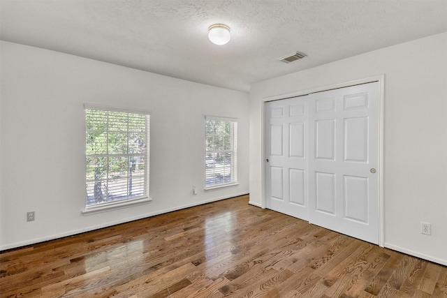 unfurnished bedroom featuring a closet, a textured ceiling, and light hardwood / wood-style flooring