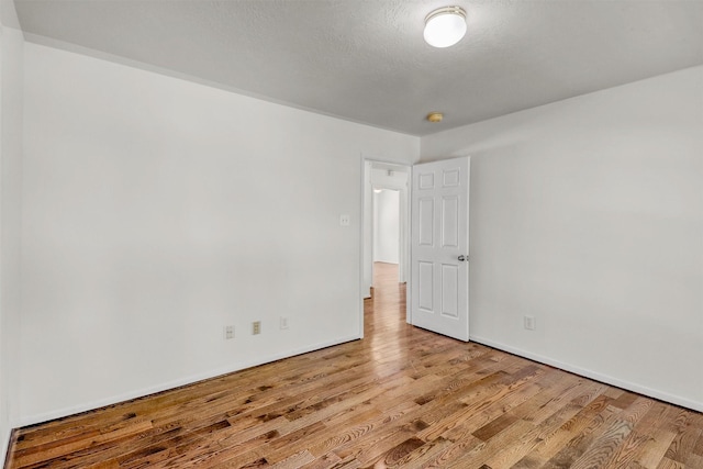 unfurnished room with a textured ceiling and light wood-type flooring