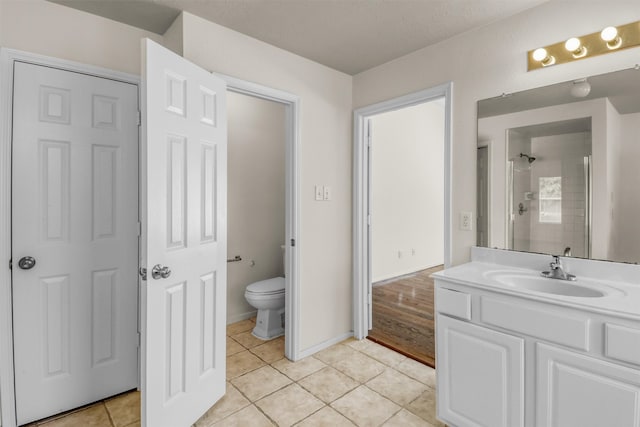 bathroom with tile patterned floors, toilet, vanity, and a tile shower