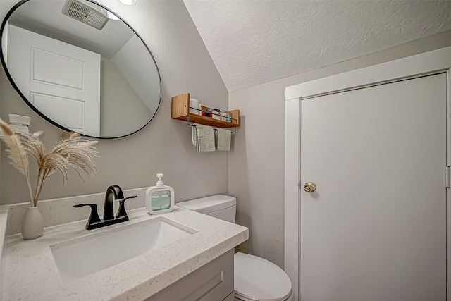 bathroom featuring vanity, toilet, a textured ceiling, and vaulted ceiling