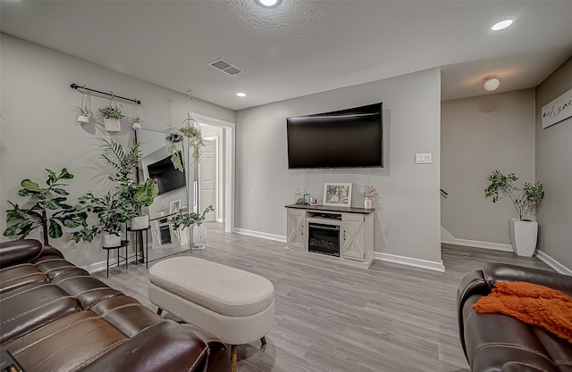 living room with light hardwood / wood-style floors and a textured ceiling