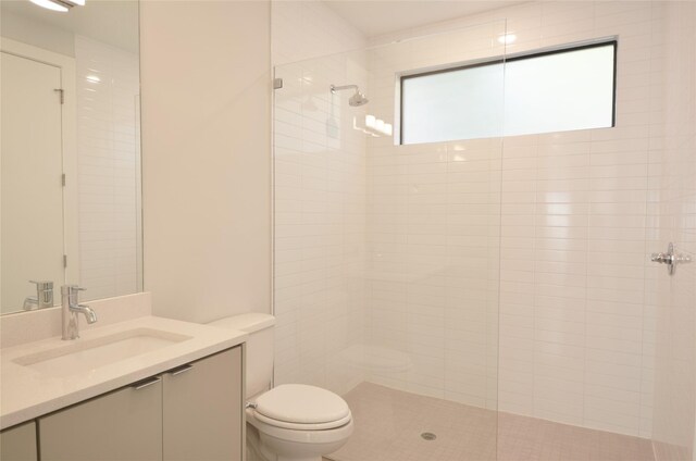 bathroom featuring vanity, toilet, and tiled shower