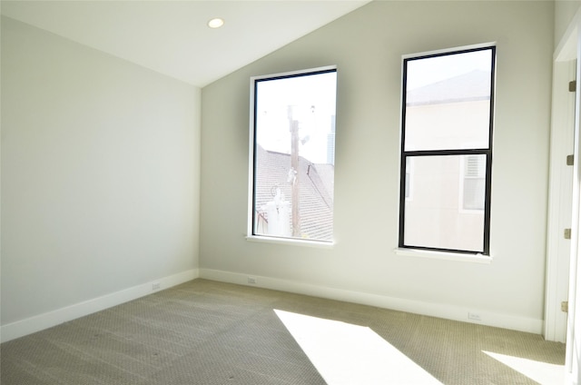 carpeted spare room featuring vaulted ceiling